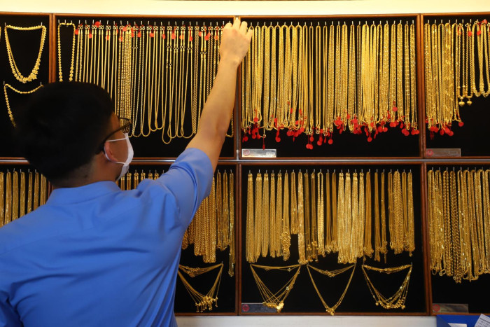 A person in a blue shirt looking at a display of gold necklaces.