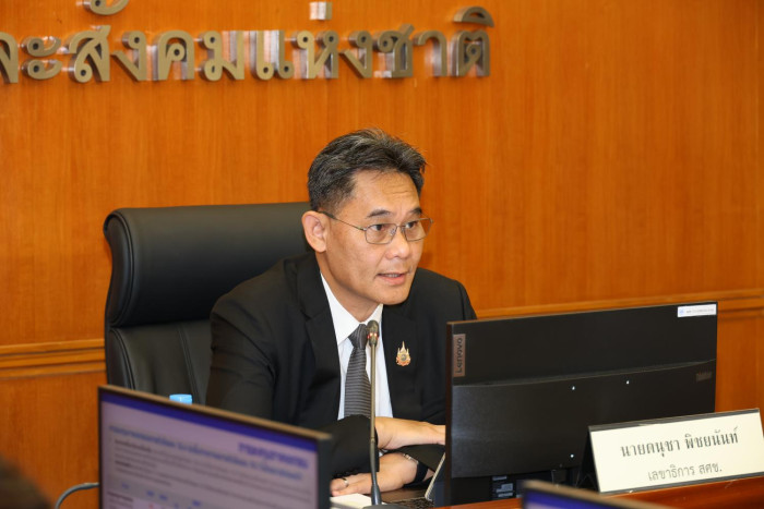 A man in a suit sitting at a desk in an office.