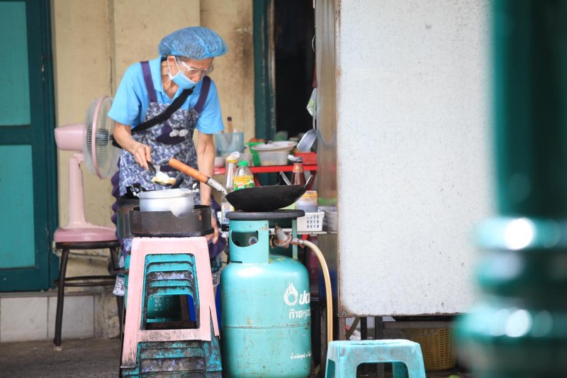 A woman prepares street food using gas. Authorities capped the cooking gas price to ease the impact of volatile crude prices. Apichart Jinakul