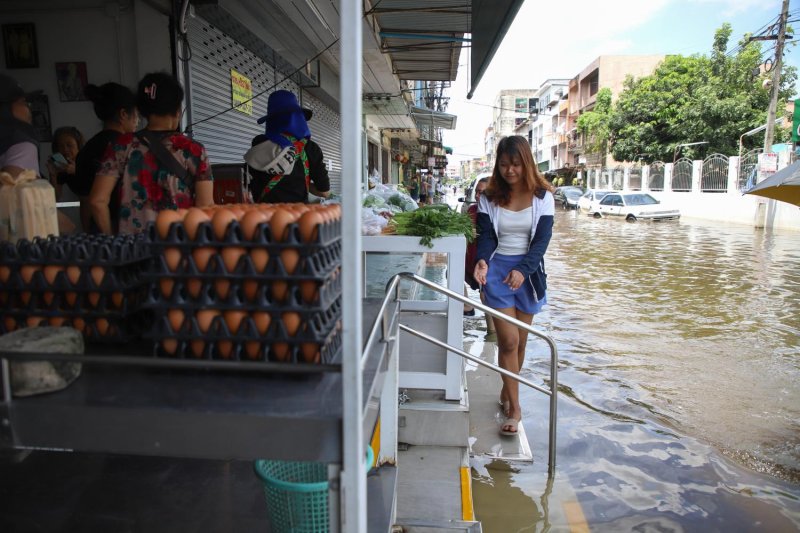 A food vendor manages to keep a shop open on heavily flooded Nawamin 24 Road. (Photo: Varuth Hirunyatheb)