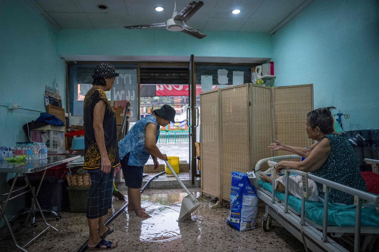 People clear standing water from their home after heavy rain in Bangkok.