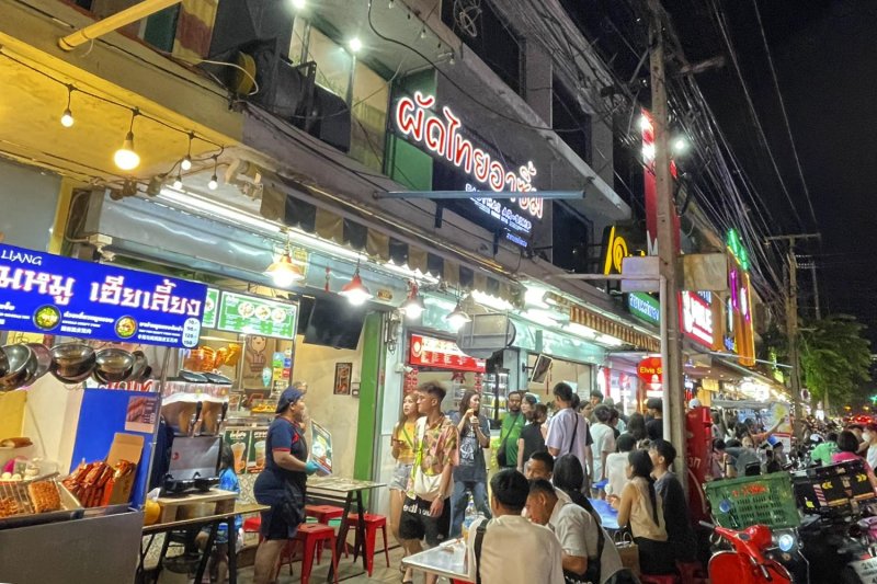 Customers dine outdoors at a Bangkok restaurant, while others browse the fare on offer. Pattarawadee Saengmanee