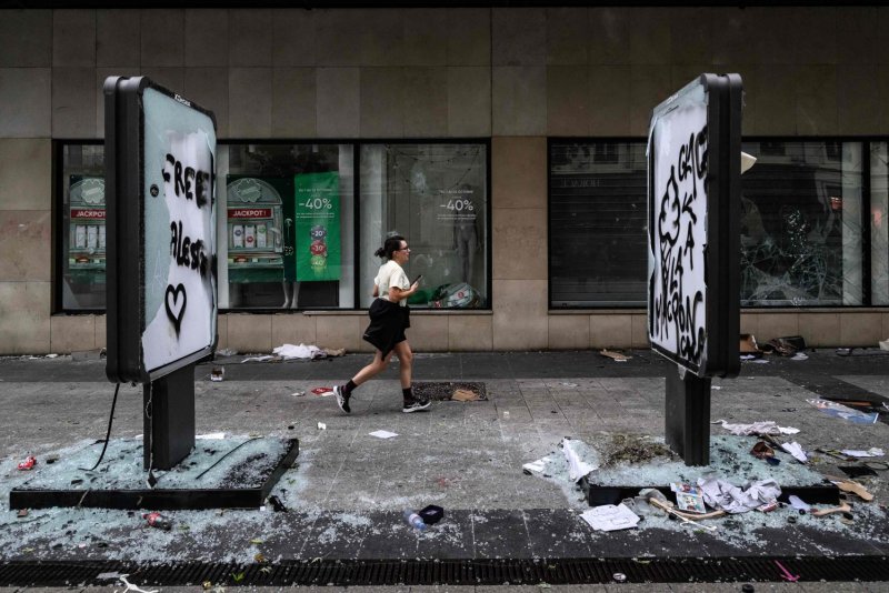 A pedestrian runs past broken shop windows in Lyon a day after rioting and looting during a nationwide protest against the high cost of living in France on Oct 18. The prime minister said 1,200 people were arrested as part of protests on Oct 17, and 150 police were hurt during clashes. AFP